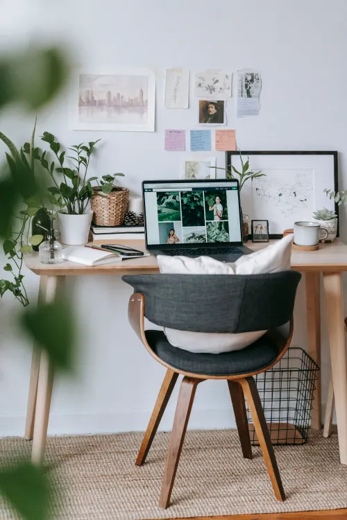 Creative home workspace with laptop plants and mood board