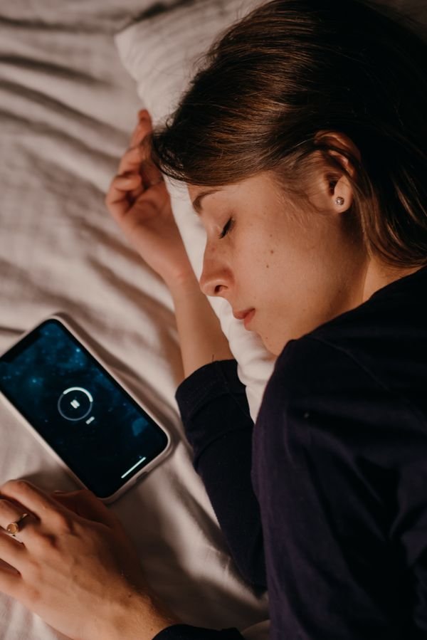 Woman lying in bed next to a phone left for the night