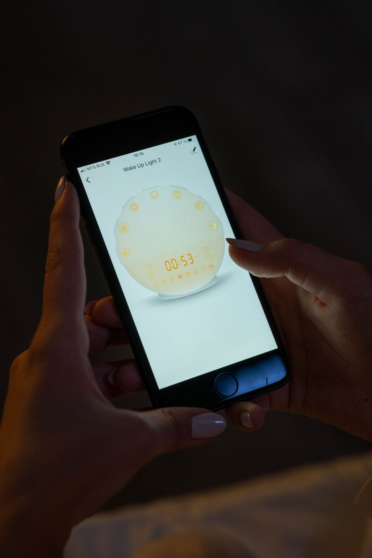 Person holding an iPhone that shows a wake up light alarm app