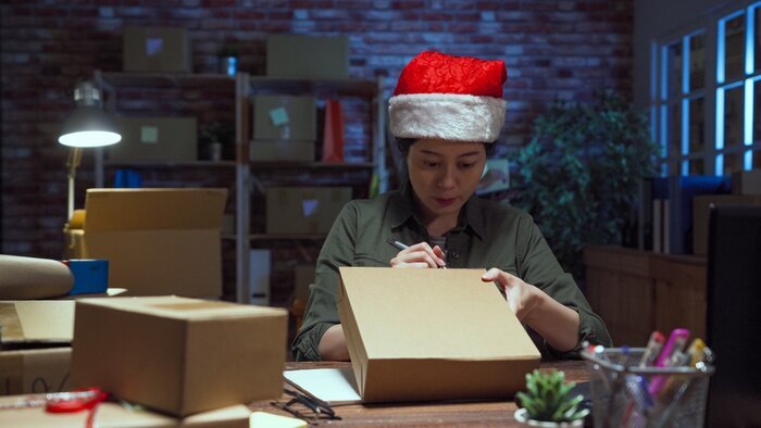 Small business owner packing cardboard parcels for Christmas delivery