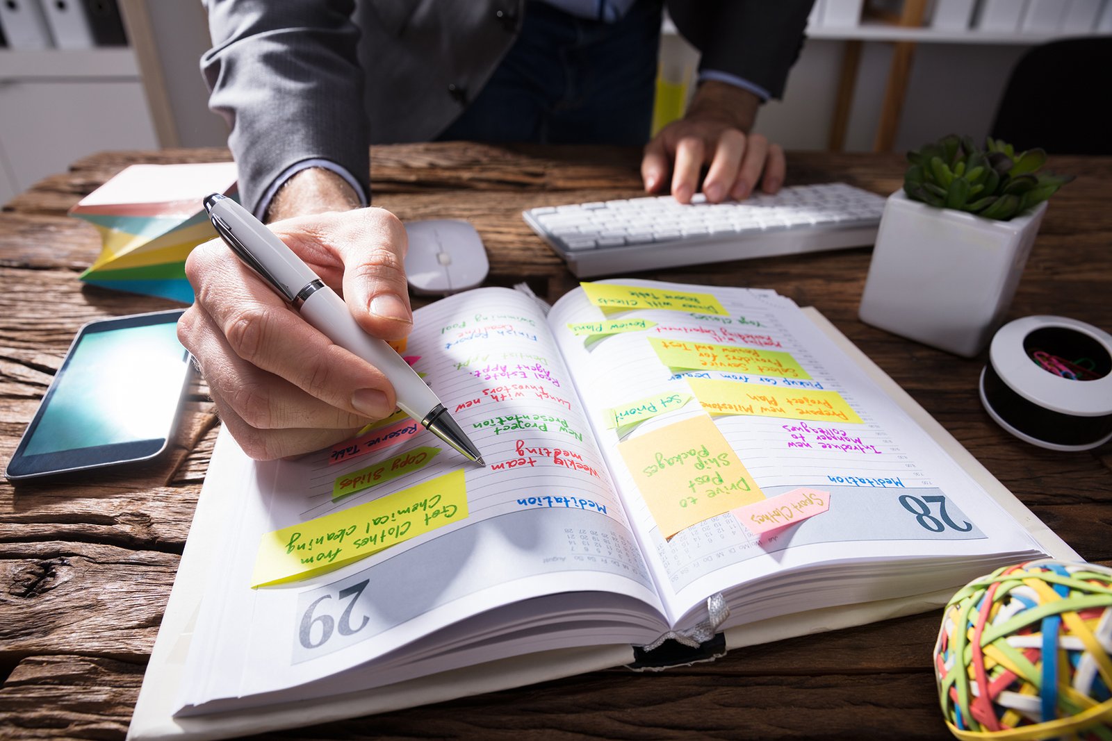 Person writing priorities in a planner to organize the day