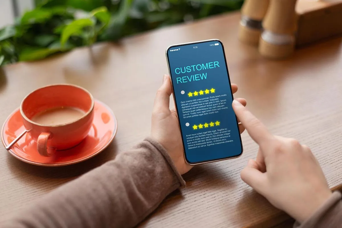 Hands holding a phone showing a five star customer review screen